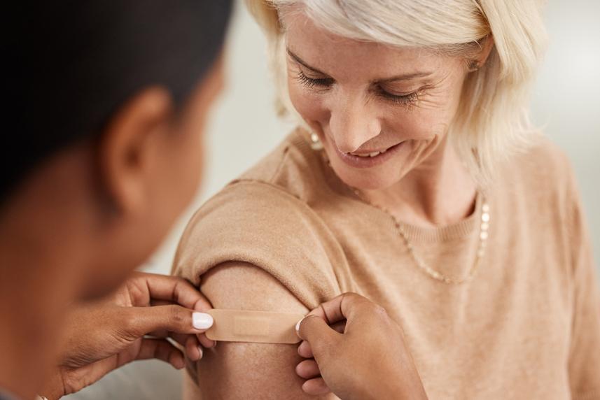Doctor putting a bandaid on a women who just got a shot